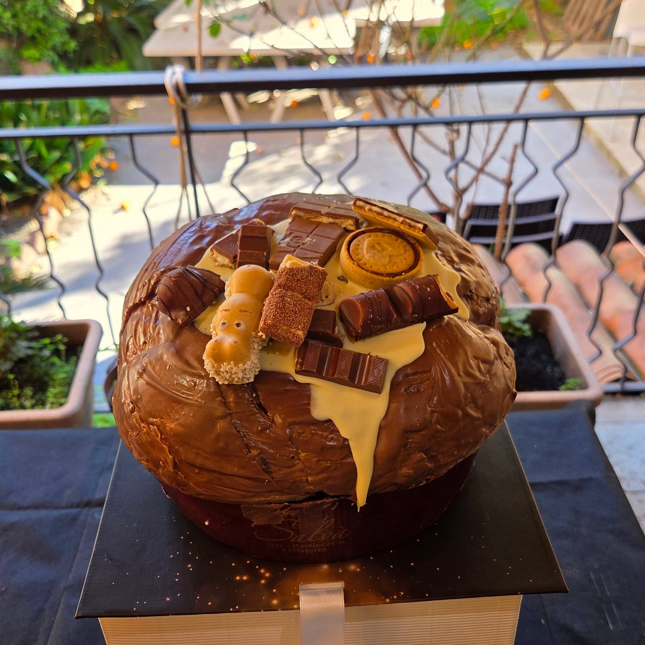 Panettone alla nocciola decorato con barrette di cioccolato e biscotti in superficie